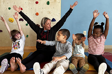 a teacher and children exercising on the floor