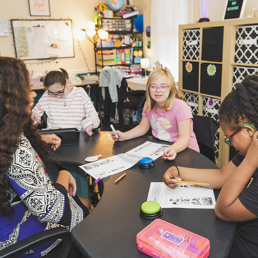 Students and staff working together at a classroom table